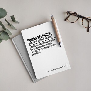 May include: A white notebook with black text that reads "HUMAN RESOURCES NOUN. (HYOO-MUHN RU-ZAW-SUHZ) SOMEONE THAT OPERATES AS THE OFFICE LAWYER, PSYCHOLOGIST, PLANNER, TEACHER, PEACEMAKER AND DETECTIVE UNOFFICIALLY. SEE ALSO BUSY BODY, NAME HERE"