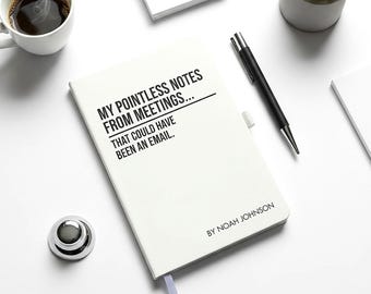 May include: A white notebook with the text "MY POINTLESS NOTES FROM MEETINGS... THAT COULD HAVE BEEN AN EMAIL." A black pen, a cup of coffee, a small succulent plant, and a silver desk bell are also on the white surface.