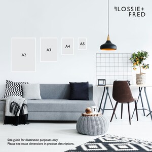 May include: A modern living room scene featuring a gray sofa with decorative pillows and a blanket. Above the sofa, four framed art prints labeled A2, A3, A4, and A5 are displayed. The room includes a desk, chair, and a patterned rug. The text "FLOSSIE + FRED" is visible.