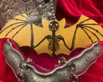 Esqueleto de murciélago pintado sobre lienzo recortado de madera de murciélago dorado
