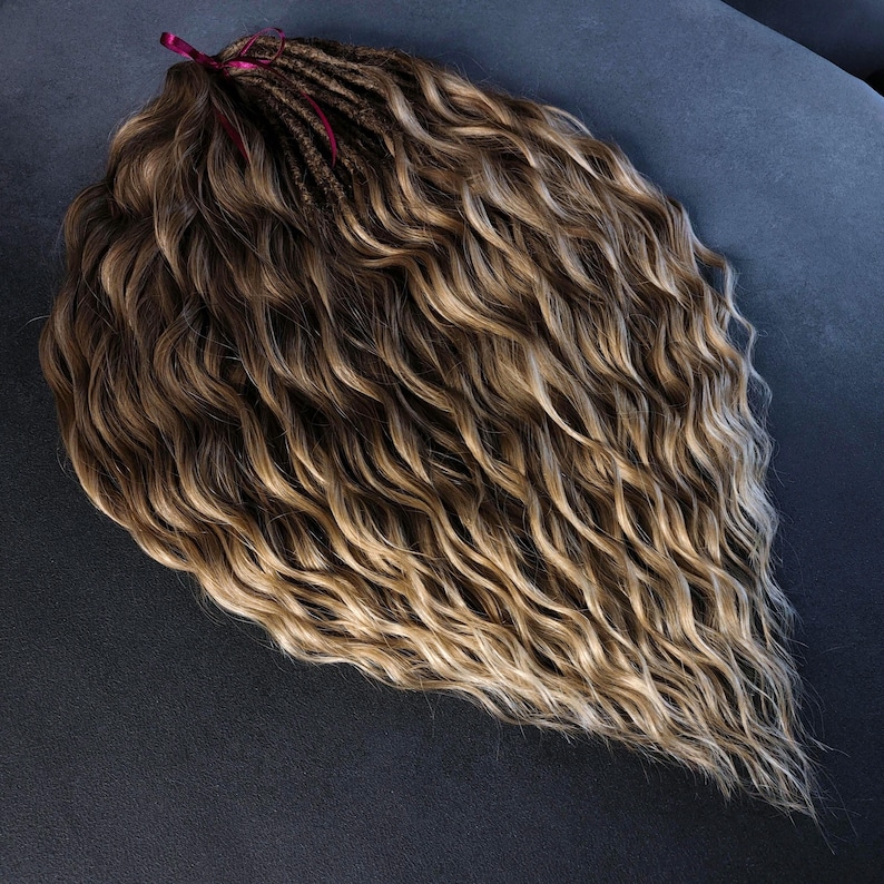 K&ouml;nnte beinhalten: Eine lange, wellige, braune und blonde Ombre-Haarverl&auml;ngerung mit einem burgunderfarbenen Band, das oben gebunden ist.