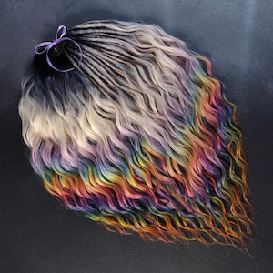 May include: A set of rainbow dreadlocks with a wavy texture. The dreadlocks transition from black to white and then to a vibrant array of colours, including pink, yellow, orange, and blue. A purple ribbon is tied at the top.
