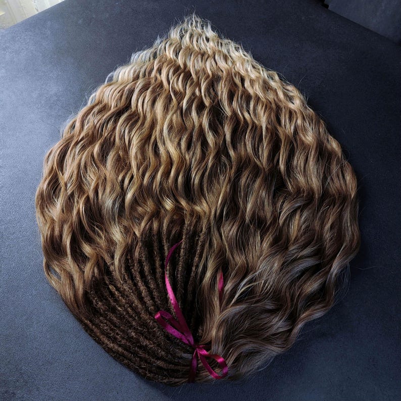 K&ouml;nnte beinhalten: Ein B&uuml;ndel welliger menschlicher Haarverl&auml;ngerungen in Braun und Blond mit einem burgunderfarbenen Band, das um den unteren Teil gebunden ist.