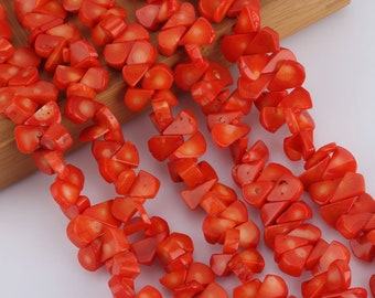 May include: A strand of orange coral beads, each bead is a unique irregular shape, some are triangular, some are rounded, and some are a combination of both. The beads are strung on a clear thread.