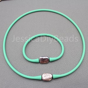 May include: A set of two turquoise silicone bracelets with silver metal accents. The bracelets are both round and have a smooth finish.
