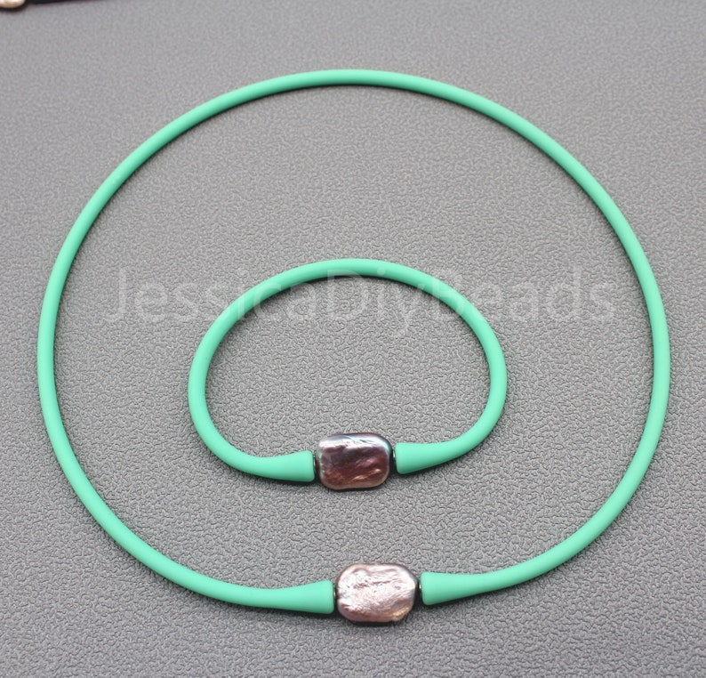 May include: A set of two turquoise silicone bracelets with silver metal accents. The bracelets are both round and have a smooth finish.