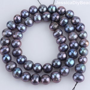 Può includere: Una collana di perle iridescenti grigio scuro. Le perle sono rotonde e lisce, e hanno un leggero luccichio. Le perle sono infilate su un filo nero.