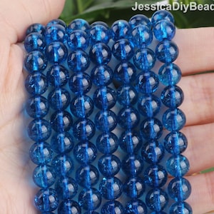 May include: A strand of round, blue, glass beads with a sparkly, iridescent finish. The beads are approximately 8mm in diameter.