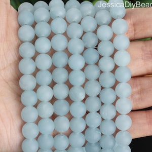 May include: A strand of light blue frosted glass beads. The beads are round and have a matte finish.