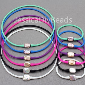 May include: A set of 10 colorful silicone necklaces with a pearl-like charm in the center of each. The necklaces are arranged in a circle, with the largest necklace on the outside and the smallest necklace on the inside. The necklaces are available in a variety of colors, including white, black, pink, purple, blue, and green.