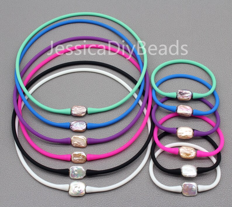 May include: A set of 10 colorful silicone necklaces with a pearl-like charm in the center of each. The necklaces are arranged in a circle, with the largest necklace on the outside and the smallest necklace on the inside. The necklaces are available in a variety of colors, including white, black, pink, purple, blue, and green.
