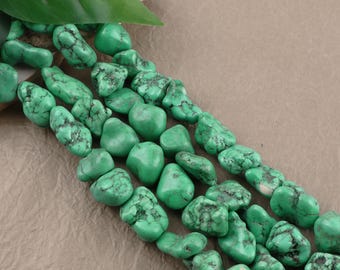 May include: A strand of irregular, tumbled turquoise beads featuring a vibrant green hue with dark, web-like matrix patterns throughout. The stones are polished to a smooth finish and are strung together in a continuous, multi-row arrangement.