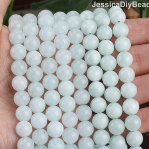 May include: A strand of light blue round gemstone beads. The beads are smooth and polished, with a subtle shimmer.