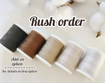 May include: Five spools of thread in different shades of brown, beige, and gray. The spools are arranged in a row from left to right, with the darkest shade on the left and the lightest shade on the right. The text "Rush order" is written in large, bold letters above the spools. The text "Add-on option" is written below the spools, with a line above and below it. The text "See details in description" is written below the line.