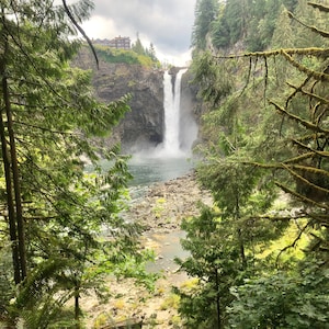 Peut inclure: Une vue d'une cascade qui dévale une falaise rocheuse, entourée d'arbres verdoyants. L'eau est claire et bleue, et la végétation environnante est vibrante.