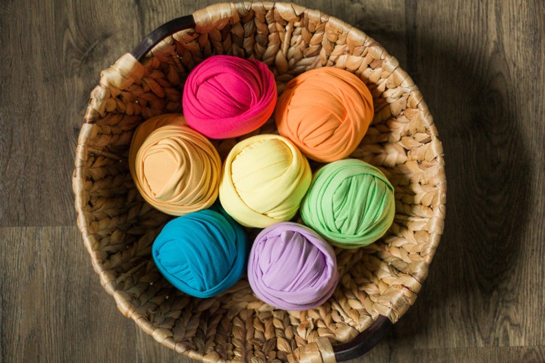 May include: A wicker basket filled with colorful yarn balls in shades of orange, yellow, green, blue, purple, and pink.