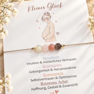 Könnte beinhalten: Ein zartes Armband mit vier runden Edelsteinperlen in Creme, Hellrosa, Pfirsich und Grau, getrennt durch kleine goldfarbene Metallabstandshalter auf einer dünnen braunen Kordel, präsentiert auf einer Karte mit einer Illustration einer schwangeren Person.