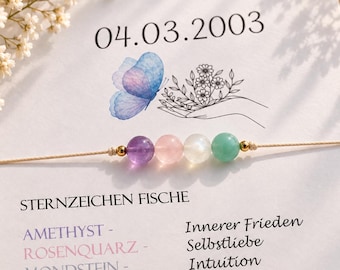 Puede incluir: Una pulsera de cuentas con cuatro piedras redondas en morado, rosa, blanco y verde, separadas por pequeñas cuentas doradas en un cordón fino. La pulsera se presenta sobre una tarjeta blanca impresa con la fecha 04.03.2003, una mariposa azul y el texto STERNZEICHEN FISCHE.