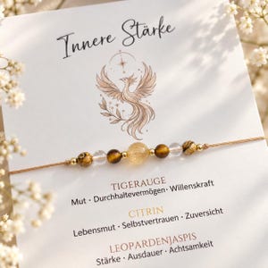 Könnte beinhalten: Ein zartes Armband auf einem beigen Faden mit einem zentralen gelben Edelstein, flankiert von braunen Tigerauge-Perlen, klaren Quarzperlen und kleinen goldfarbenen Zwischenelementen. Es liegt auf einer weißen Karte mit dem Text Innere Stärke.