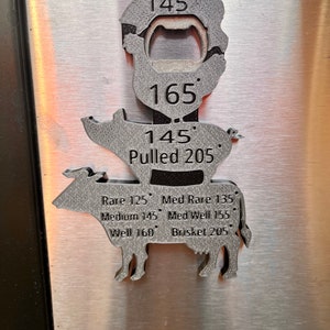 May include: A metal pig-shaped bottle opener with a thermometer on the side. The thermometer has markings for different temperatures, including rare, medium rare, medium, medium well, well, and brisket. The thermometer also has a built-in bottle opener.