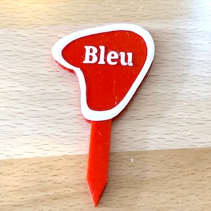Puede incluir: Marcador de jard&iacute;n de pl&aacute;stico rojo con borde blanco y la palabra "Bleu" en letras blancas.