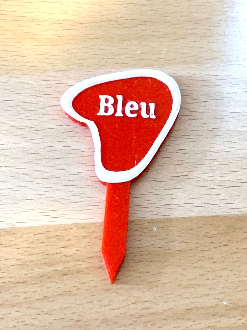 Puede incluir: Marcador de jard&iacute;n de pl&aacute;stico rojo con borde blanco y la palabra "Bleu" en letras blancas.