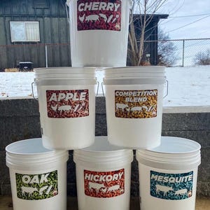 Pu&ograve; includere: Sei secchi di plastica bianca con manici in metallo. Ogni secchio ha un'etichetta con un sapore diverso: Cherry, Apple, Competition Blend, Oak, Hickory e Mesquite. Le etichette presentano testo e illustrazioni.