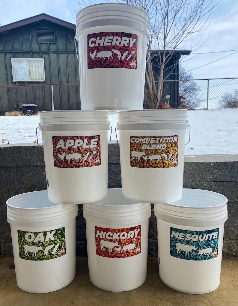 Pu&ograve; includere: Sei secchi di plastica bianca con manici in metallo. Ogni secchio ha un'etichetta con un sapore diverso: Cherry, Apple, Competition Blend, Oak, Hickory e Mesquite. Le etichette presentano testo e illustrazioni.