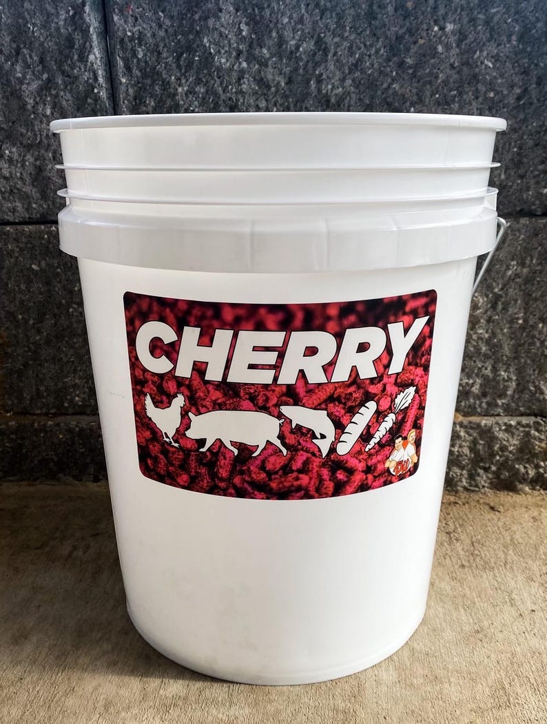 Pu&ograve; includere: Un secchio di plastica bianco con un'etichetta rossa e bianca. L'etichetta recita "CHERRY" a grandi lettere bianche. Sagome di pollo, maiale, pesce e verdure sono anche sull'etichetta. Il secchio ha un manico in metallo.