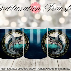 May include: Three white ceramic mugs with a sublimation transfer design of a blue marlin fish jumping out of the water in a stained glass style circle. The background is a blue and green ocean scene.