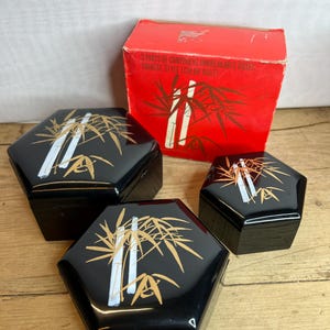 May include: Three black hexagonal boxes with gold bamboo patterns and a red box with text. The boxes have a glossy finish. The red box has text that reads "3 PARTS OF COMPONENT UNBREAKABLE BOXES CHINESE STYLE (COLOR RUST)".