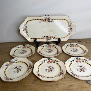 May include: Set of six white octagonal dessert plates with a floral and bird design in black, orange, and yellow. The set also includes a matching rectangular serving platter.