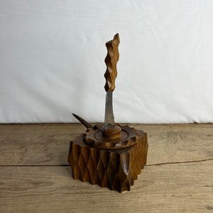 May include: A vintage wooden butter dish with a carved design. The dish has a lid with a small knife and a decorative handle. The wood is a warm brown colour, and the dish sits on a wooden surface.