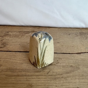 Op de afbeelding: Een keramische zoutstrooier met een beige basis en blauwe bloemaccenten. De strooier heeft een rechthoekige vorm met een licht afgeronde bovenkant. Groene en bruin geschilderde bladeren lopen vanaf de basis. De strooier staat op een houten oppervlak.