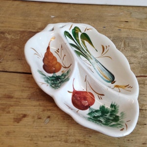 Puede incluir: Un plato de servir de cerámica blanca con tres secciones, cada una con un diseño de verduras pintado a mano. El plato está decorado con pintura verde, marrón y roja.