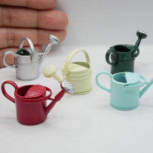 Puede incluir: Cinco regaderas metálicas en miniatura de diferentes colores: plata, amarillo, verde, azul y rojo. Las regaderas tienen un pico y un asa.