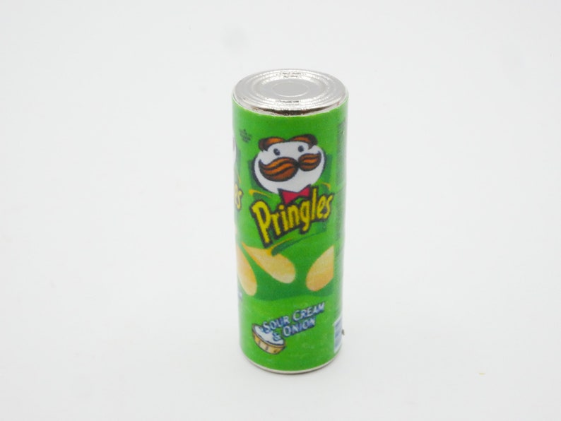 Pu&ograve; includere: Una lattina di Pringles verde e gialla con un coperchio bianco. La lattina ha un personaggio dei cartoni animati con i baffi e un papillon. Il testo sulla lattina dice "Pringles" e "Sour Cream & Onion".