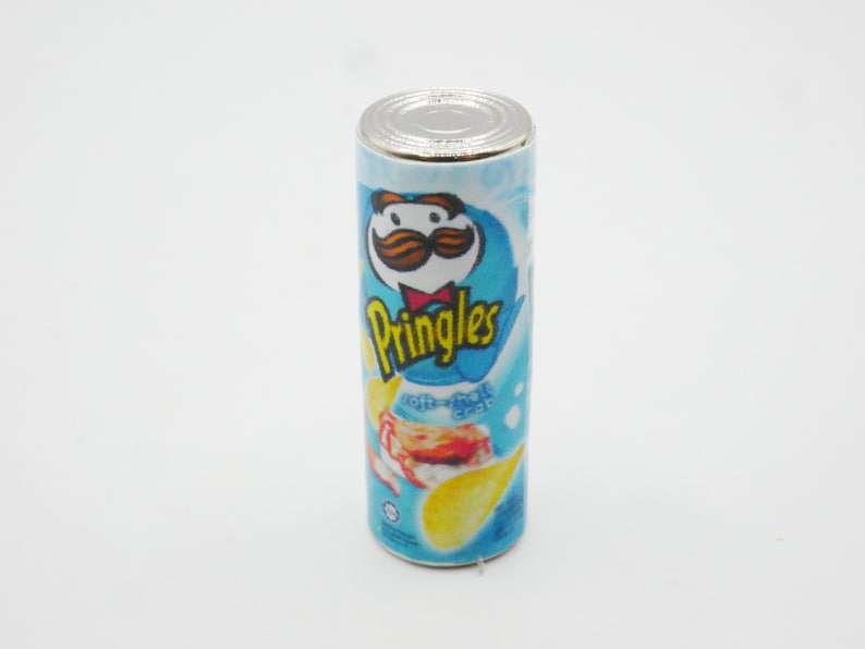 Pu&ograve; includere: Una lattina di patatine Pringles blu e bianca con un baffo rosso e bianco sul davanti. La lattina dice "Pringles" in lettere bianche e "Crema acida e cipolla" in lettere bianche pi&ugrave; piccole.