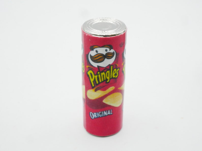 Pu&ograve; includere: Una lattina rossa e bianca di patatine Pringles Original. La lattina presenta un personaggio dei cartoni animati con i baffi e una patatina.