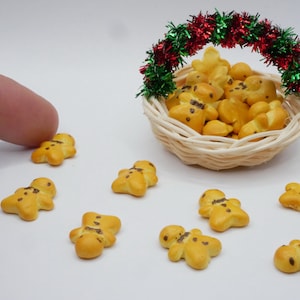 May include: A basket filled with gingerbread men cookies decorated with chocolate chips, surrounded by individual gingerbread men cookies on a white surface.