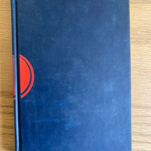 May include: A dark blue hardcover book with a red and white design on the front cover.
