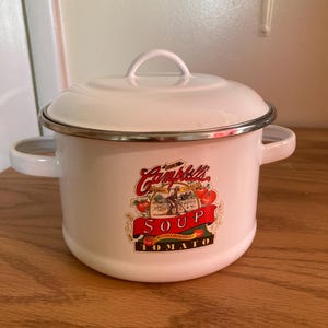 May include: White enamel Campbell's Soup pot with a lid and two handles. The pot features a Campbell's Soup Tomato label with red tomatoes and the text "SOUP CONDENSED TOMATO". The pot has a silver rim.