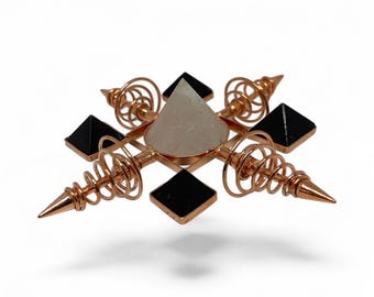 May include: A copper-colored orgone pyramid with a clear quartz crystal pyramid at the center, surrounded by four black obsidian pyramids. The design includes copper coils and pointed tips, creating a geometric and spiritual aesthetic.