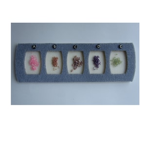 May include: A grey felt organiser with five compartments, each containing a different colour of small beads. The beads are pink, brown, light purple, dark purple, and green. The compartments are labelled A through E.