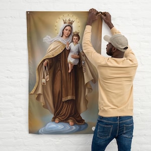 May include: A religious wall hanging depicting a woman and child, both wearing crowns and surrounded by a golden halo. The woman is dressed in brown and beige robes, holding two small framed images. The child is in white robes, standing on a cloud.