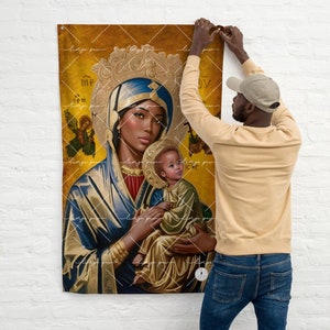 Könnte beinhalten: Eine Wandteppich mit einem Gemälde der Jungfrau Maria und dem Jesuskind. Die Jungfrau Maria ist mit dunkler Haut und einem blauen Gewand dargestellt. Das Jesuskind trägt ein gelbes Gewand. Der Hintergrund ist goldfarben mit kunstvollen Details.