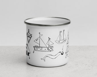 Könnte beinhalten: Weiße Emailtasse mit einer schwarz-weißen Illustration verschiedener Schiffe und nautischer Symbole. Die Tasse hat einen silbernen Rand.