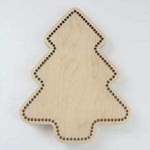 Könnte beinhalten: Ein hellfarbiger Holzausschnitt in Form eines Weihnachtsbaums. Die flache Holzoberfläche weist eine Reihe von gleichmäßig verteilten, kleinen kreisförmigen Löchern auf, die entlang des gesamten Umfangs der Baumform eingestanzt sind.