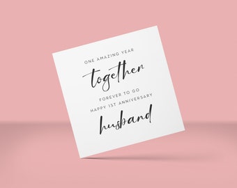 May include: A white card with black script on a pink background. The card reads "ONE AMAZING YEAR together FOREVER TO GO HAPPY 1ST ANNIVERSARY husband."