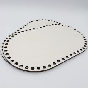 Può includere: Due basi ovali per cesti in legno. Ogni base è bianco sporco con un bordo marrone scuro e fori distanziati per la tessitura. Le basi sono impilate l'una sull'altra su uno sfondo bianco.